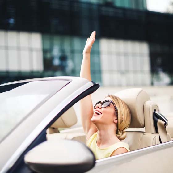Woman in convertible with hand in the air