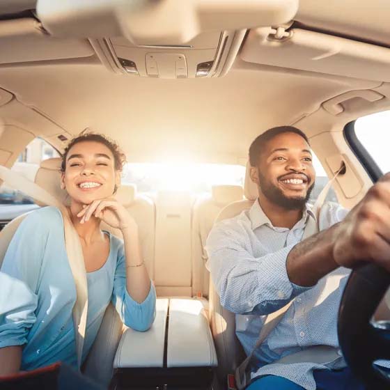 Man and woman driving car smiling 