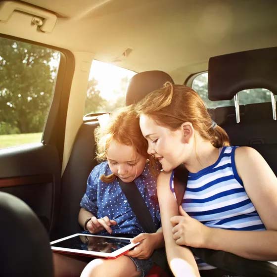 Children in back seat of car on tablet