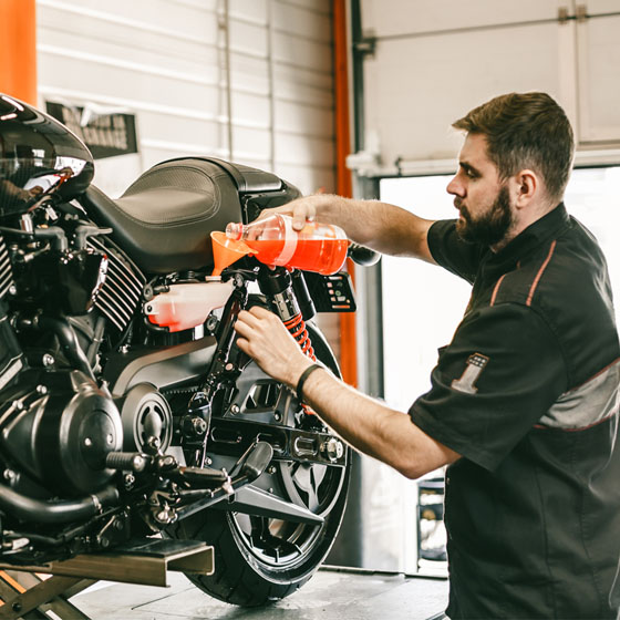 Motorcycle technician adding fluids