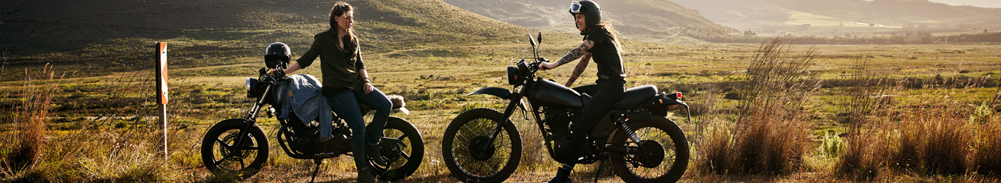 Two people on side of road with motorcycles